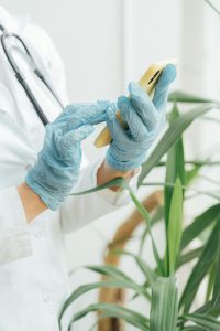 Doctor wearing gloves texts on smartphone, emphasizing healthcare and technology.